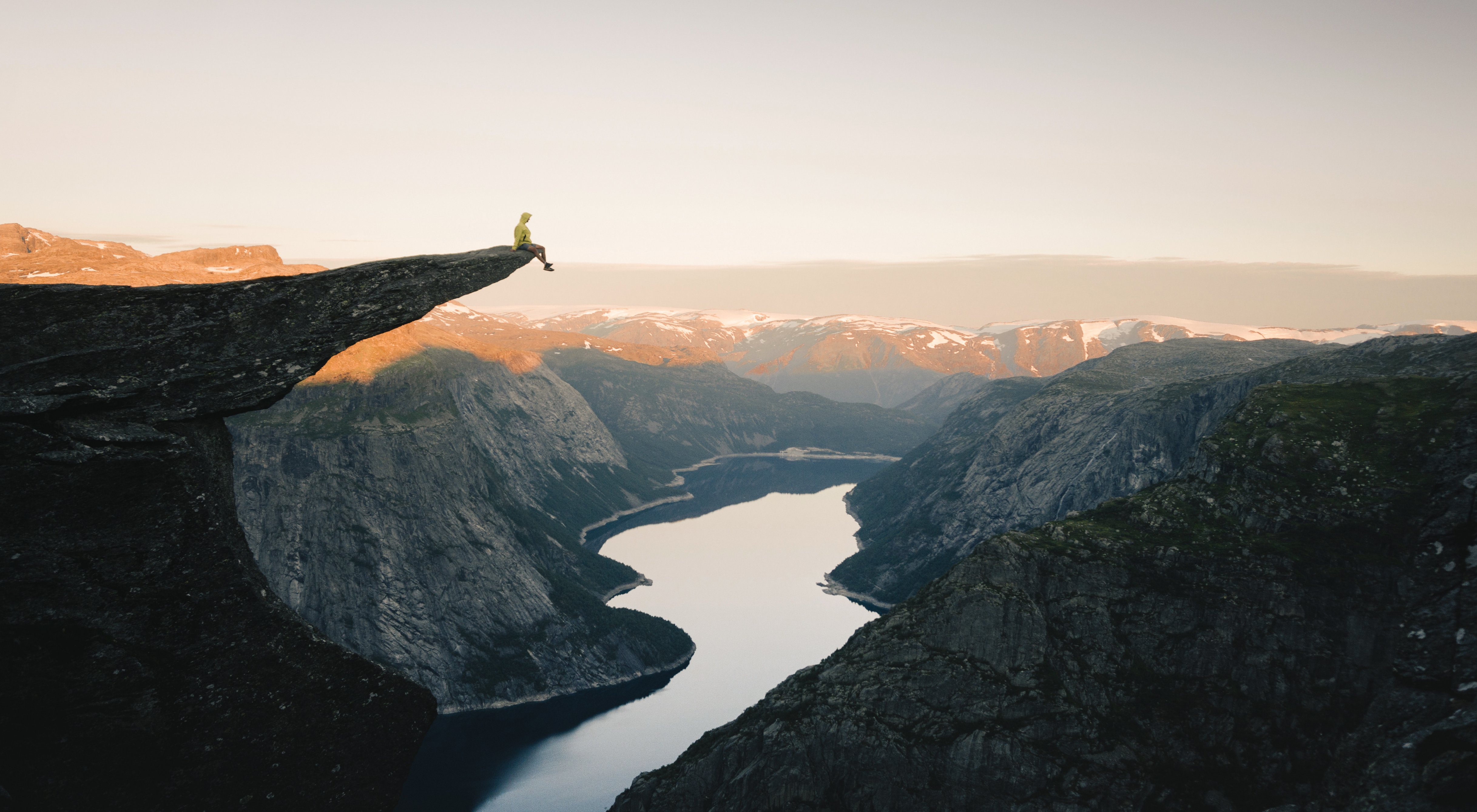 Vista image of person sat on outcrop overlooking the lake below.